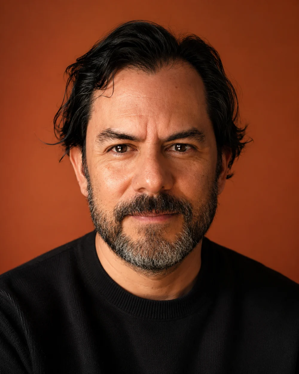 Retrato de Víctor Yoalli frente a un fondo naranja